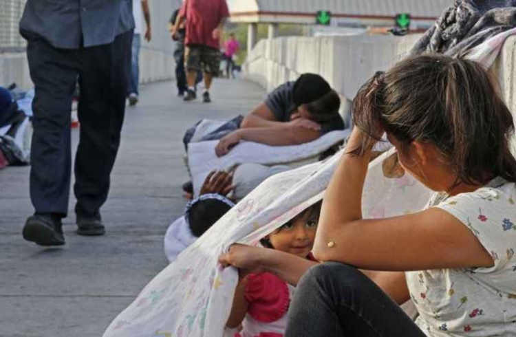 epa06850065 People enter the United States walk past two year old Jennifer and her mother Evelyn (R) sleeping along with other immigrants from Guatemala and Cuba seeking asylum waiting in the middle of the bridge to get into the United States from Matamoros, Mexico, 29 June 2018. Immigration along the Rio Grande in Texas has become a political issue, due to the controversy surrounding the US Justice Department's suspended 'Zero Tolerance' policy of criminally prosecuting all migrants entering the country illegally and the now-reversed policy of separating migrant children from their parents.  EPA/LARRY W. SMITH