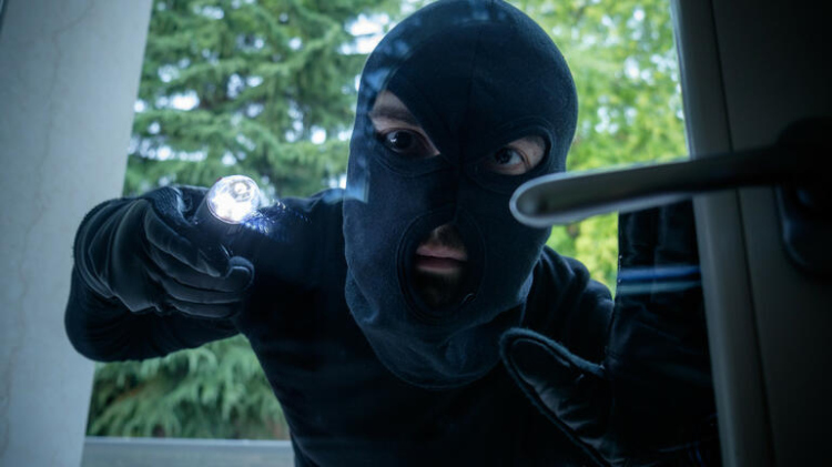 Burglar wearing a balaclava looking through the house window
