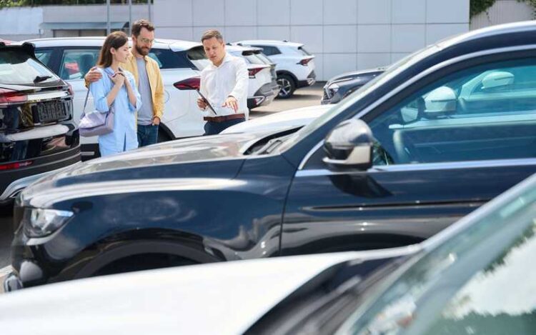 Couple chooses a car in the yard of a car dealership, a consultant helps them