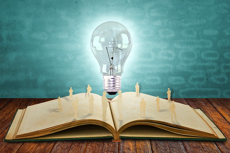 Paper cut of business people and light bulb on book