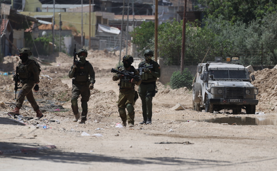 epa12136455 Israeli soliders on guard as Palestinians try to reach their houses to take care of their belongings at Tulkarem refugee camp near the West Bank city of Tulkarem, 26 May 2025. EPA/ALAA BADARNEH